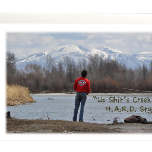 Image of guy fishing on a river wearing a HARD shirt with mountains in the back